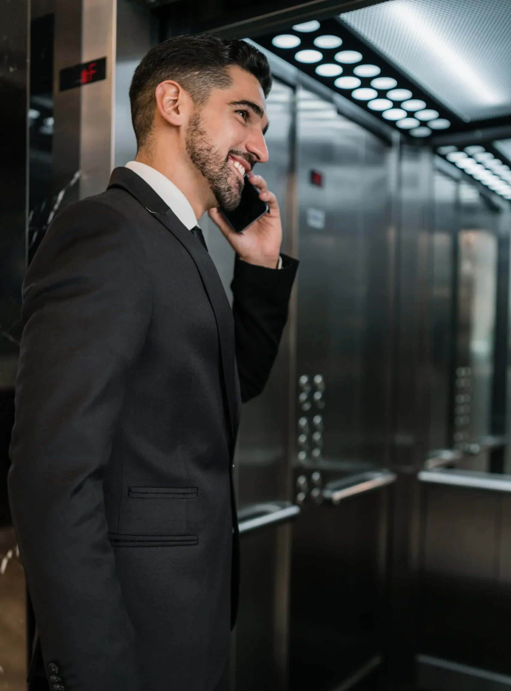 portrait-young-businessman-talking-phone-hotel-elevator-business-travel-concept